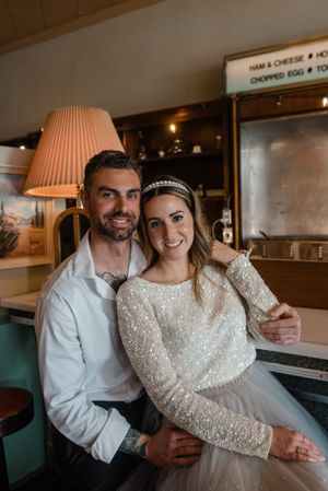 A casual portrait in a retro diner setting with vintage decor and teal booths.