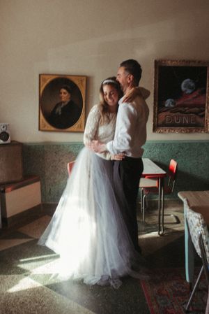 Wedding couple dancing in vintage-style room with antique portraits and retro decor.