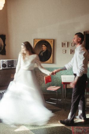 Couple dancing in vintage room with blurred motion and white wedding dress.