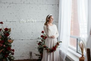 Elegant bridal scene with floral decor, white brick wall, and neon signage.