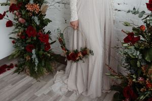 Close-up of bridal dress hem with red and pink floral arrangements.