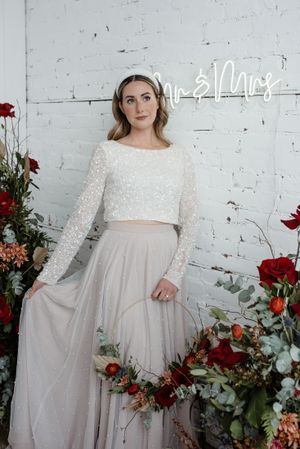 Modern bridal portrait with crop top and tulle skirt against white brick wall with red florals.