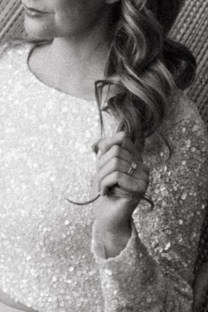 Black and white detail of sequined wedding dress and curled hair.