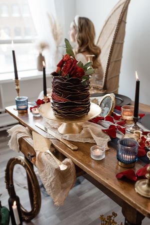 Elegant table setting with chocolate cake, red roses, and black candles in a romantic atmosphere.