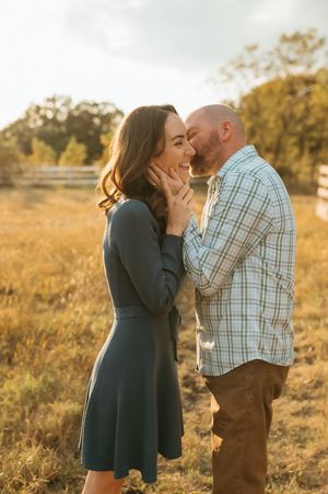 A romantic couple shares tender moments in a golden sunlit field during sunset.