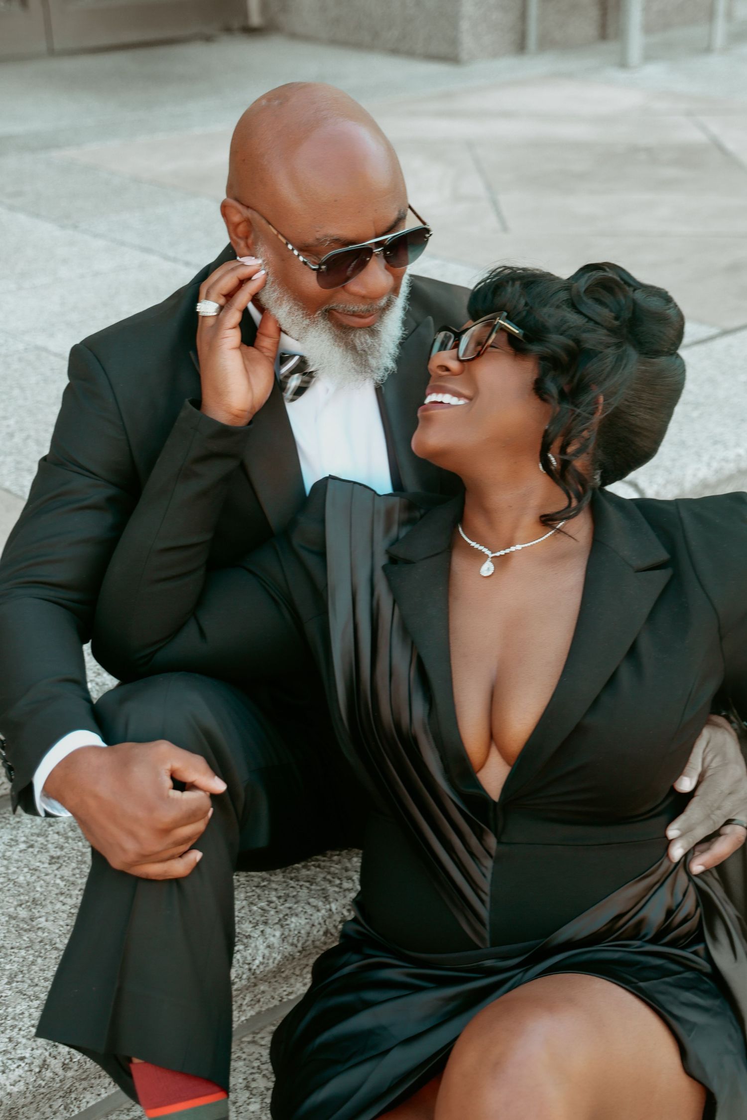 Elegant Black couple in black formal wear sitting on steps, laughing and enjoying each other.
