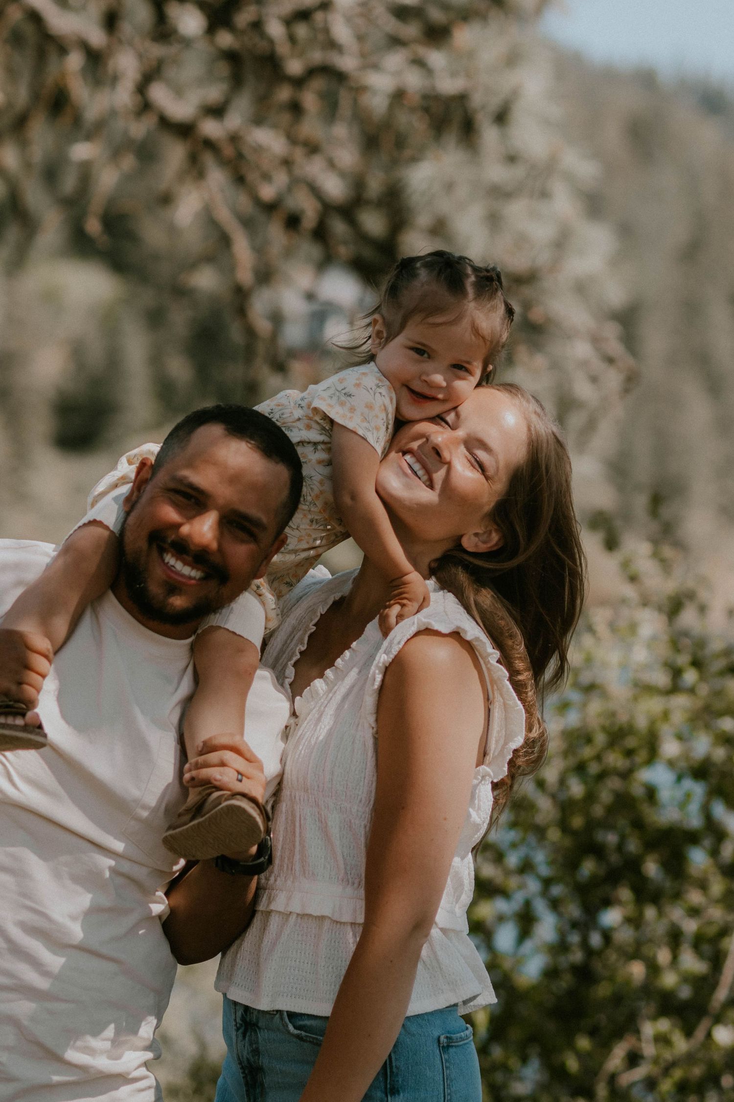 A tender family moment at sunset with parents holding their baby in warm golden light.