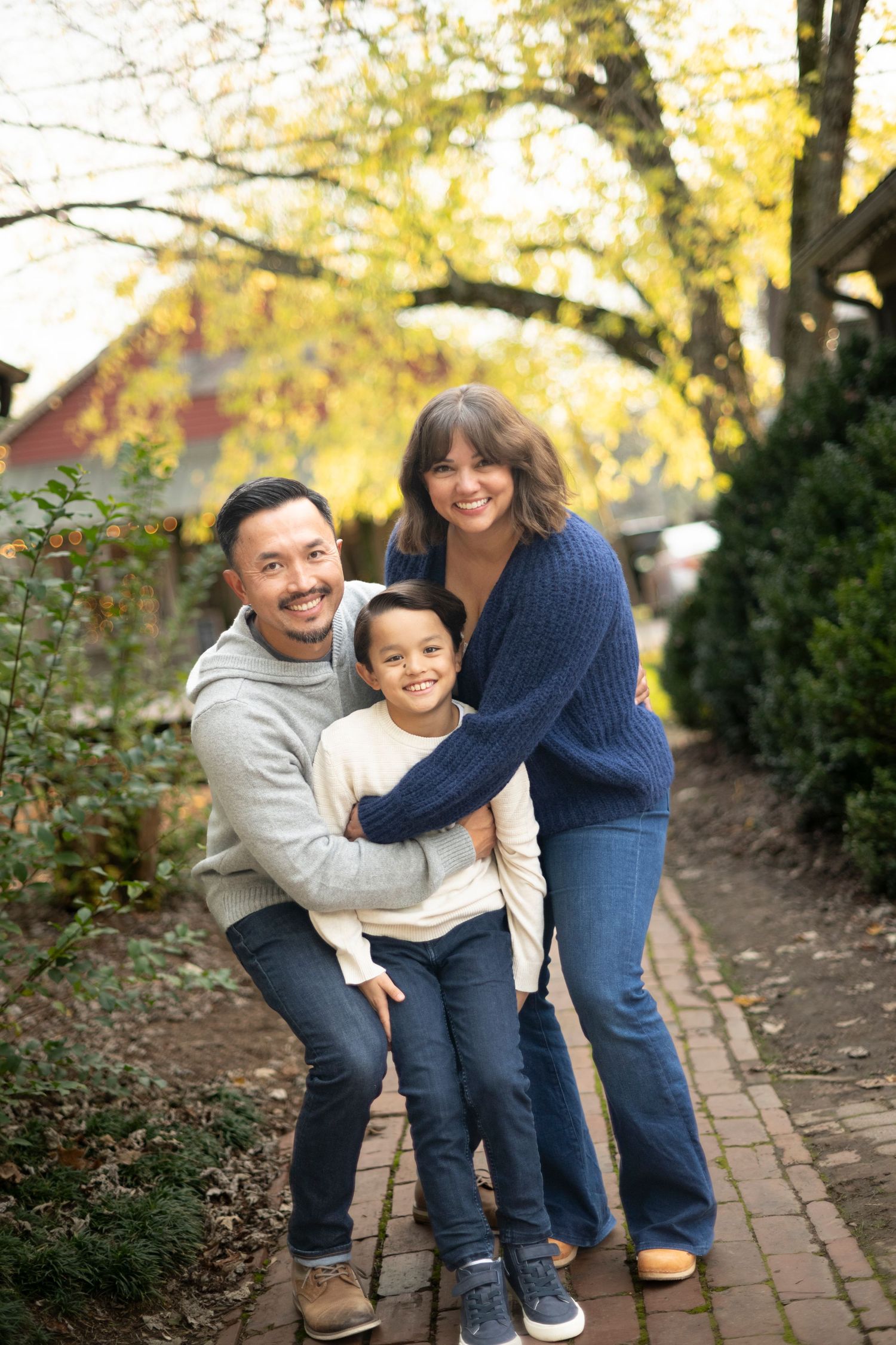 Family shares playful moment together on brick pathway surrounded by autumn trees in Leiper's Fork for their yearly family portraits.
