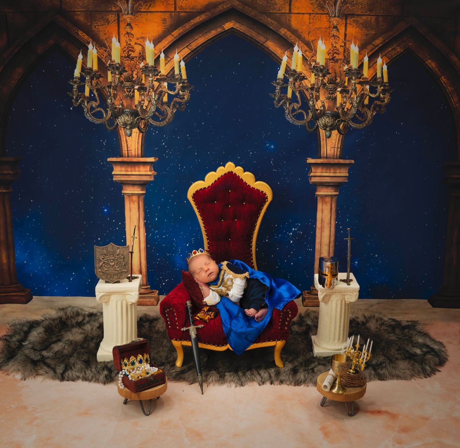 Gothic themed photo setup with elegant chandeliers and red velvet throne against starry backdrop.