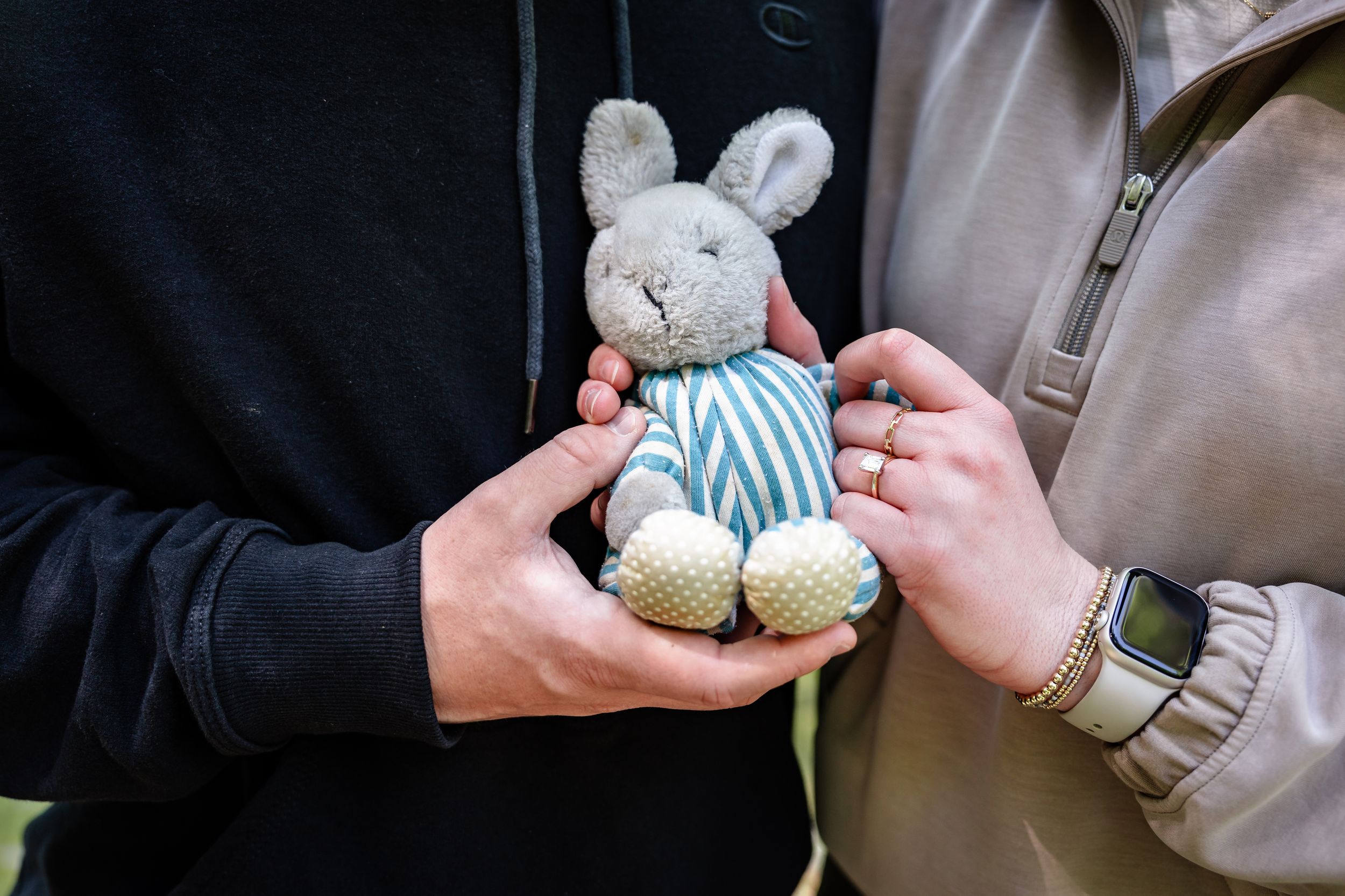Hands holding small decorative objects in an outdoor setting.