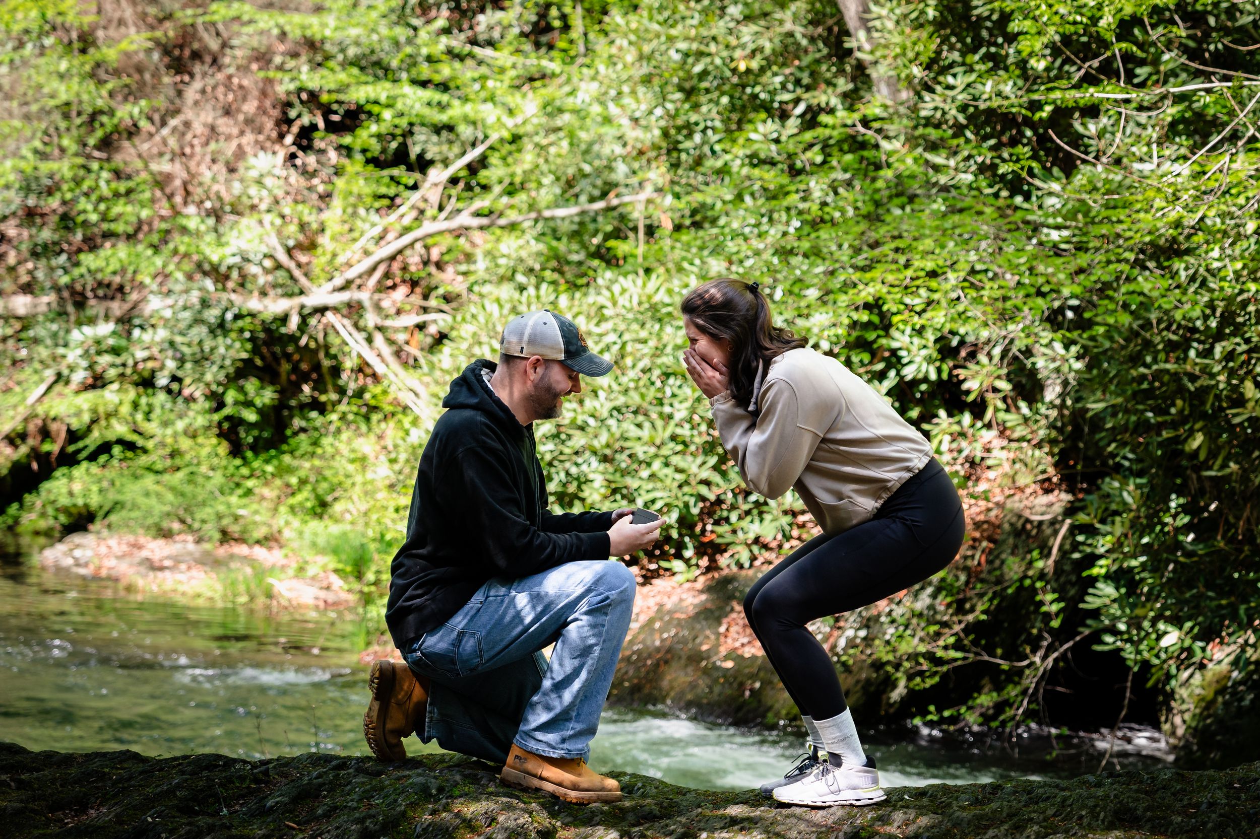 Two people explore along the banks of a crystal clear forest stream.