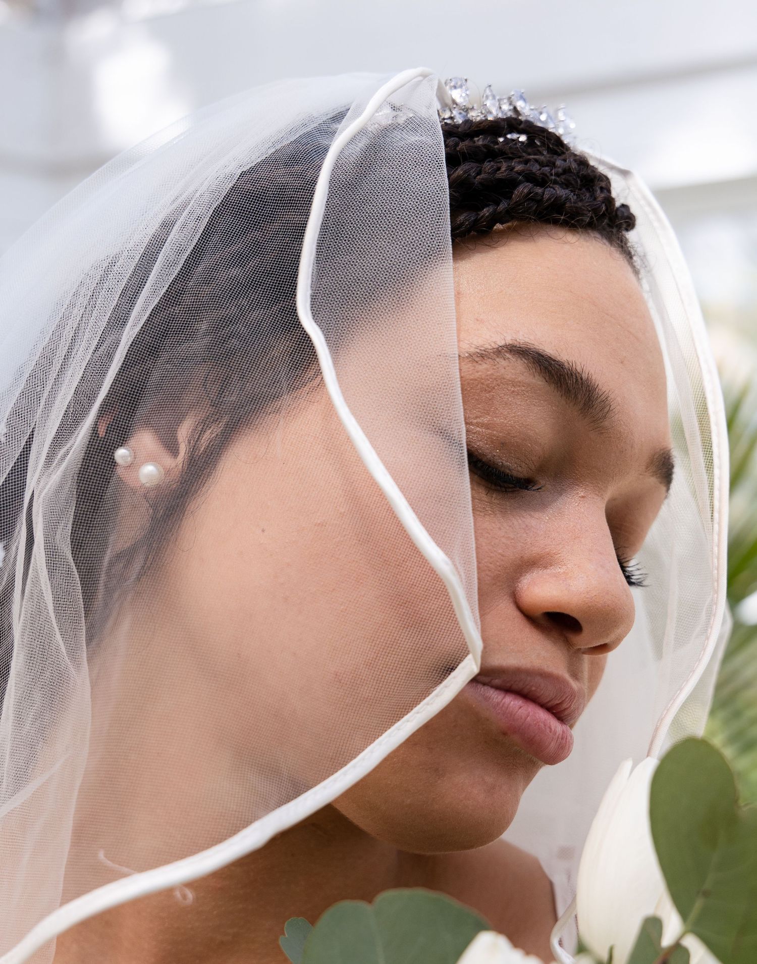 Artistic portrait of bride under sheer veil with eyes closed.