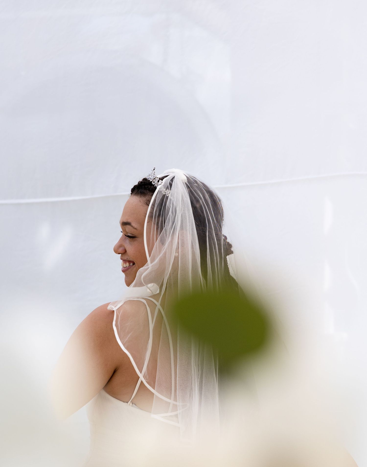 Side profile of a bride wearing a delicate veil against a light background.