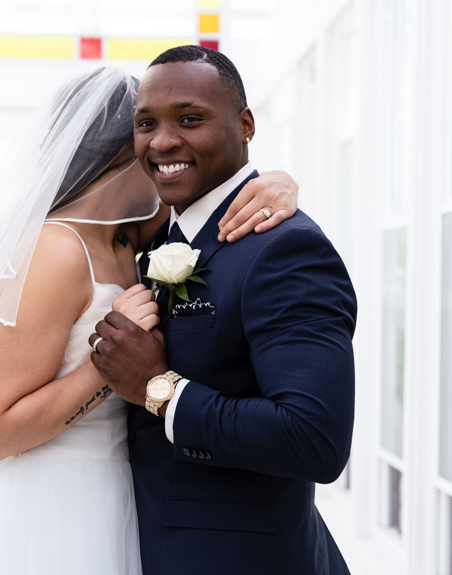 Joyful wedding moment captured as a couple embrace while wearing traditional formal attire with a white boutonniere.