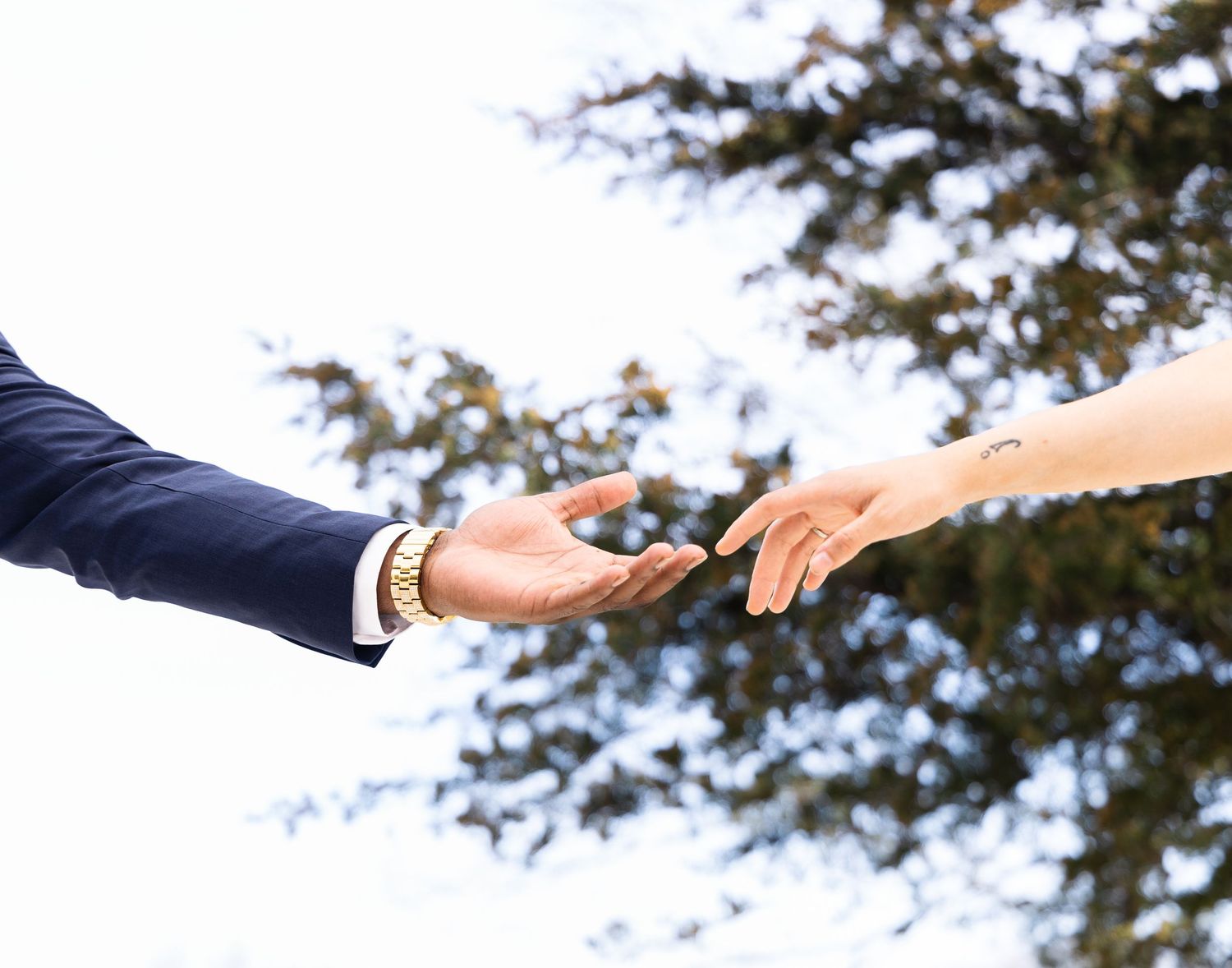 Close-up of hands reaching towards each other during a wedding ceremony.