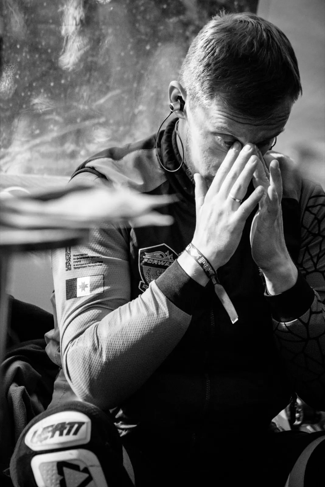 Portrait en noir et blanc d’un athlète visiblement ému, les mains couvrant son visage.