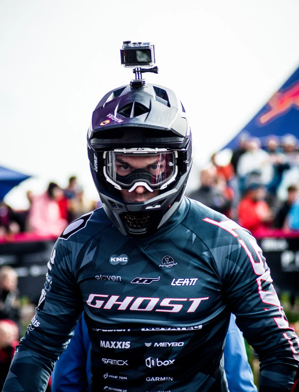 Portrait d’un rider en tenue de compétition “GHOST”, portant un casque intégral avec une GoPro fixée dessus.