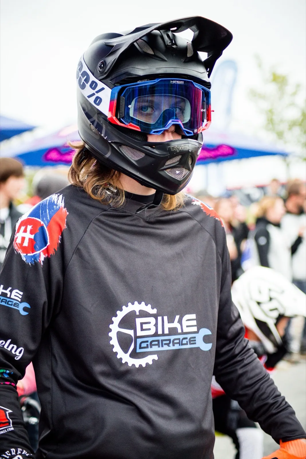 Portrait d’un rider en tenue de compétition et casque, arborant un maillot “BIKE CHALLENGE”.