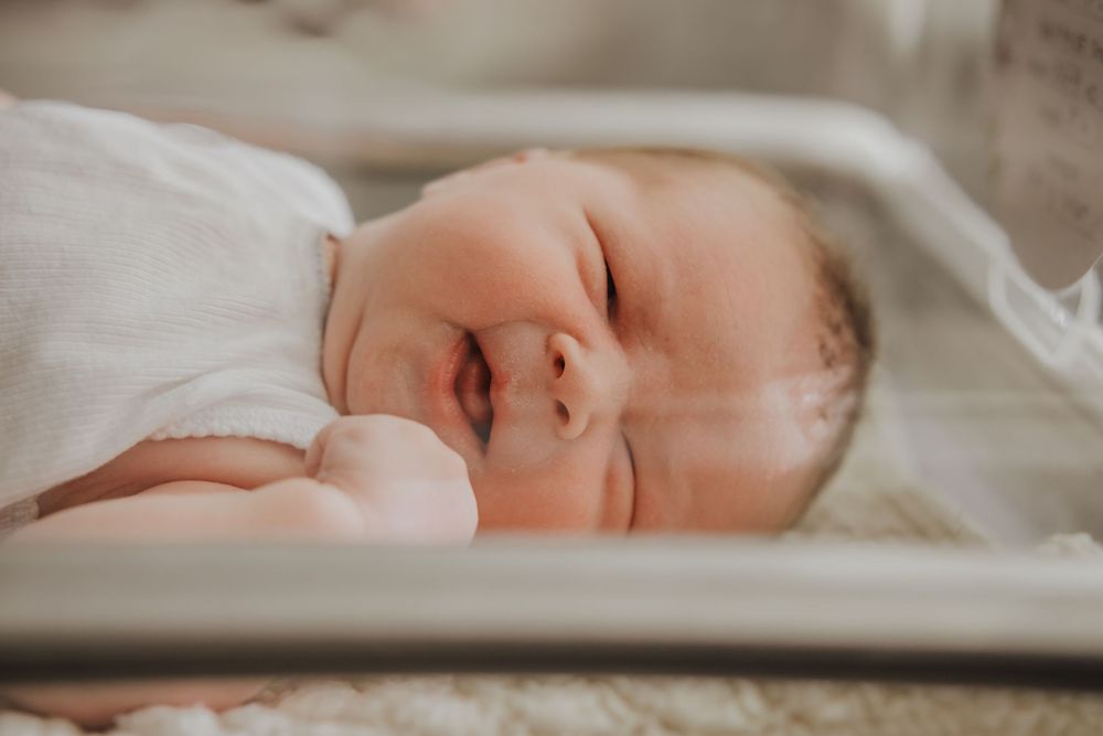 A tranquil newborn sleeps peacefully in a white bassinet with soft natural lighting.