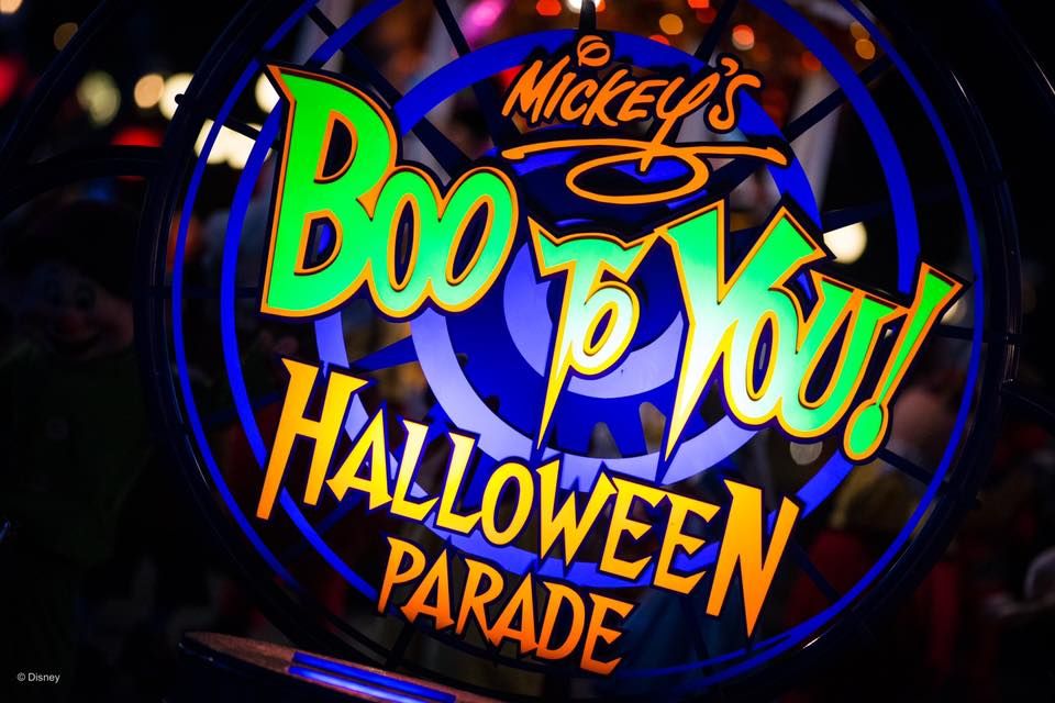 Neon sign for Mickey's Boo To You Halloween Parade glowing in bright colors against dark background.
