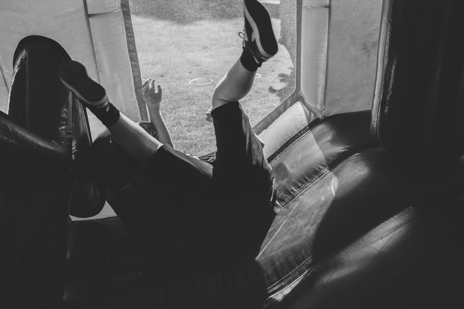 Someone relaxes on red and black inflatable furniture outside on a sunny suburban street.