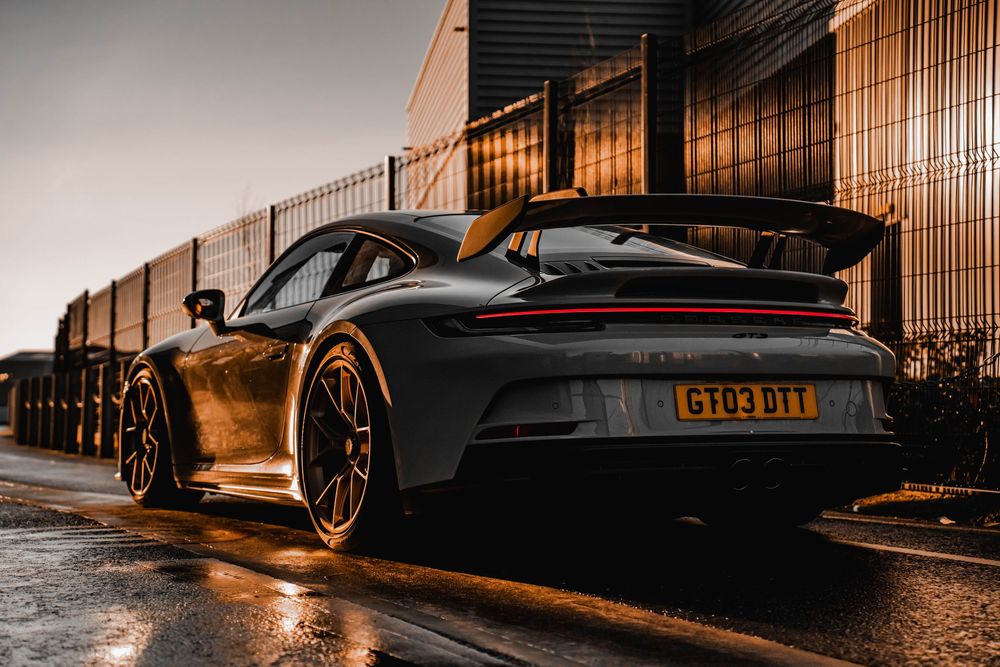 Dark Porsche 911 GT3 rear quarter view highlighting aerodynamic design and LED taillights.