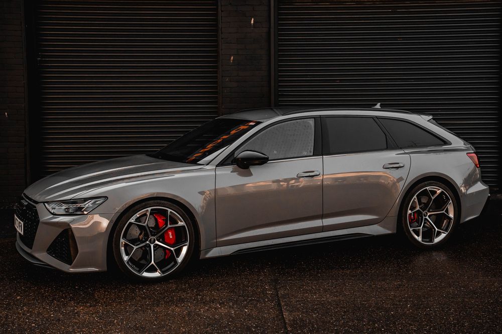 Gray Audi RS6 Avant wagon profile view showcasing sporty alloy wheels and red brake calipers.