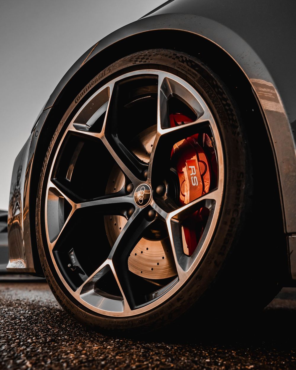 Black and bronze Porsche wheel design with red brake caliper visible through spokes.