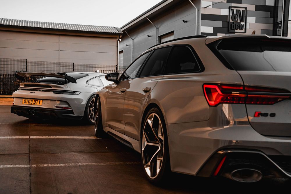 Two Audi RS6 Avants parked together in bronze and silver colorways at dusk.