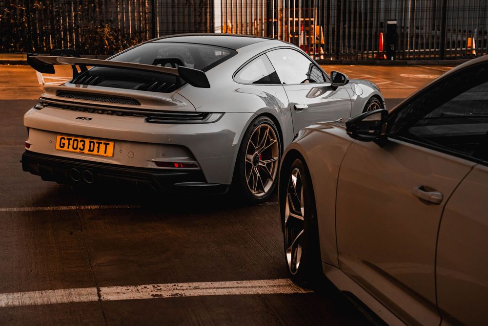 Silver Porsche 911 GT3 parked at night showing its distinctive rear wing and LED taillights.