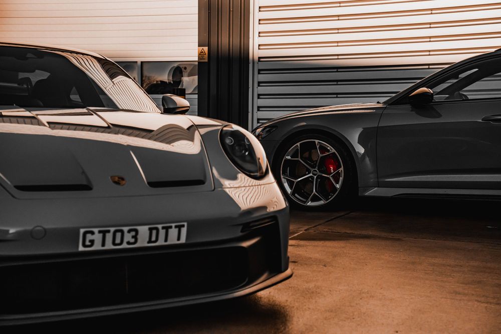 Close-up view of a Porsche GT3 front end alongside a dark performance vehicle.