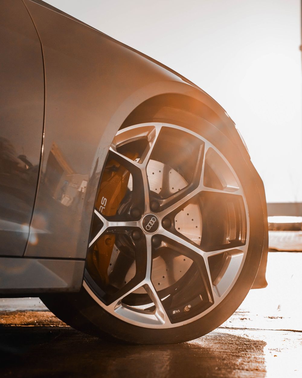 Close-up of a luxury car's wheel featuring black and silver split-spoke design and performance brakes.
