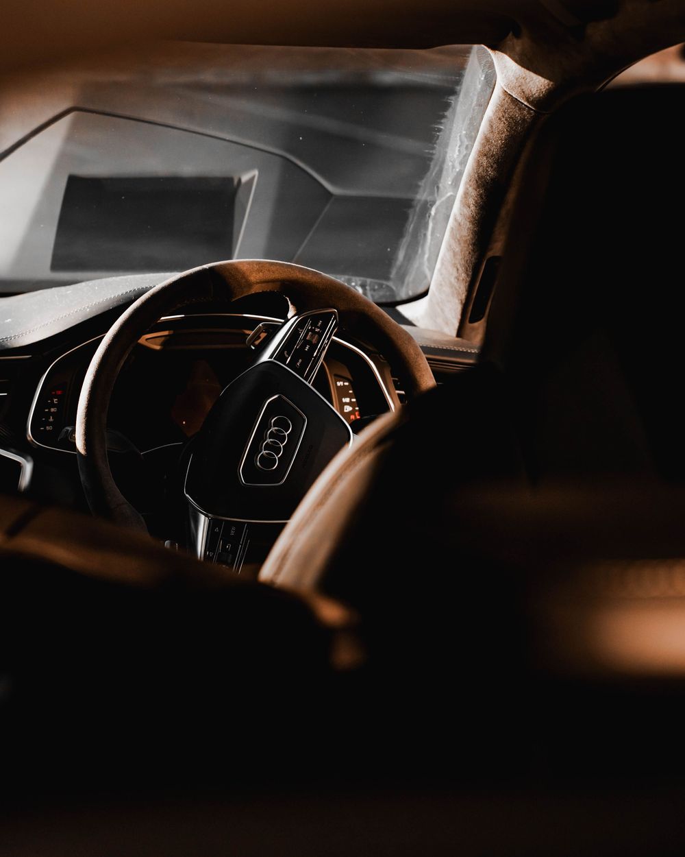 Moody interior shot of an Audi steering wheel with ambient lighting in darkness.
