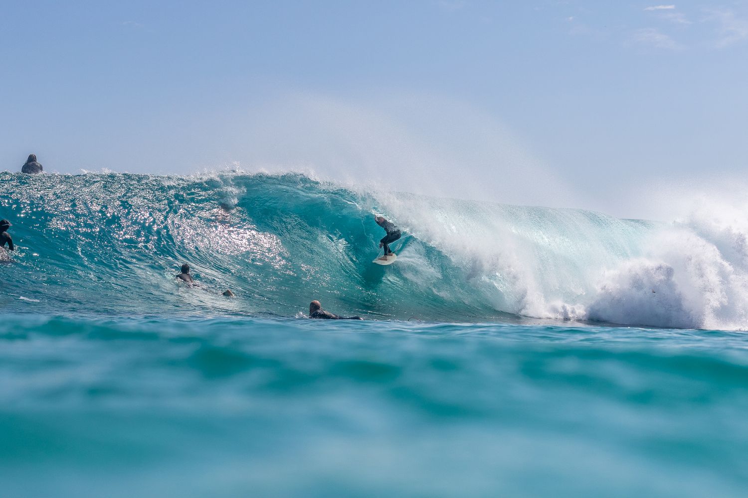 A powerful turquoise ocean wave curls and crashes with white spray in clear tropical waters.