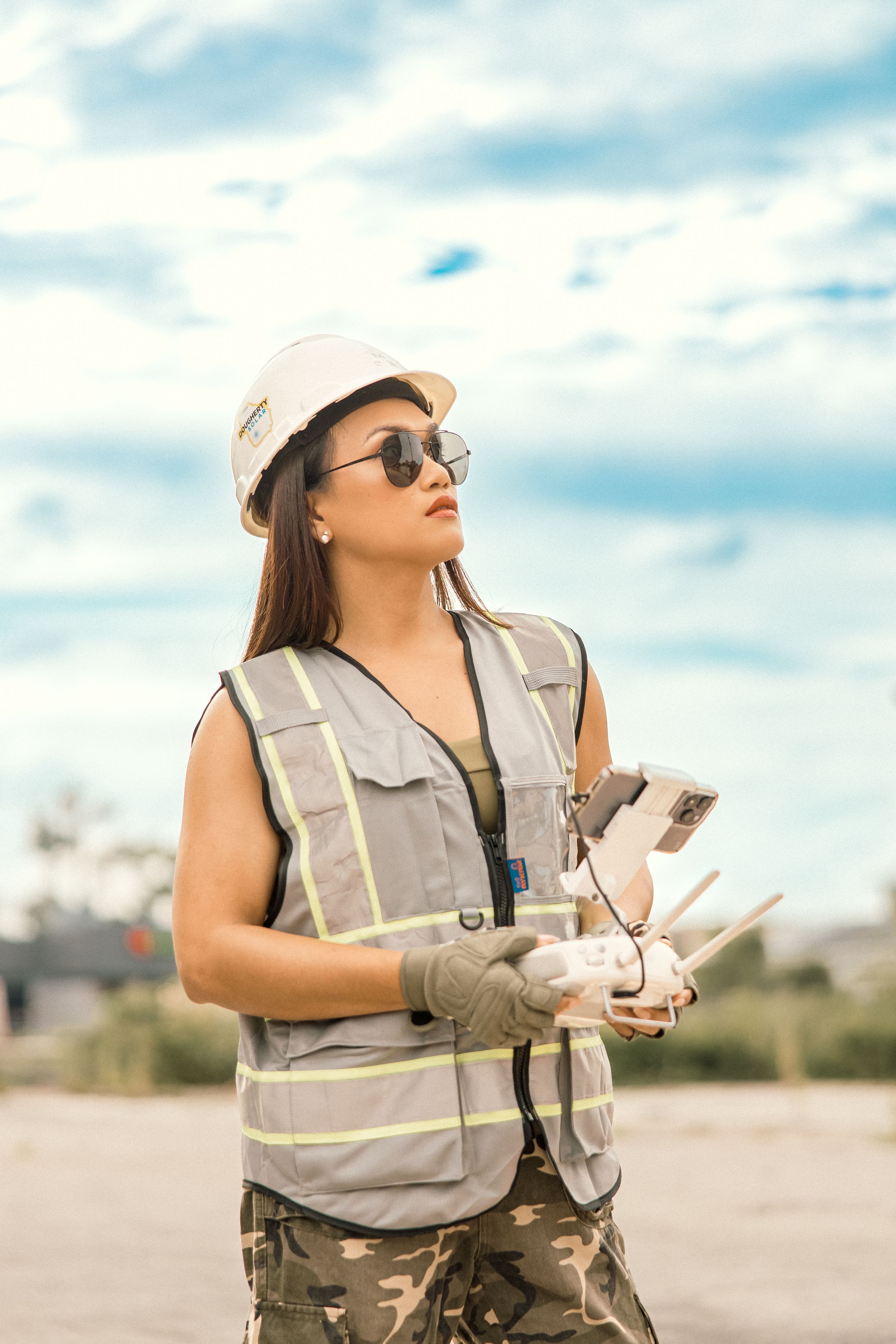 Construction worker in safety vest and hard hat reviewing documents outdoors.