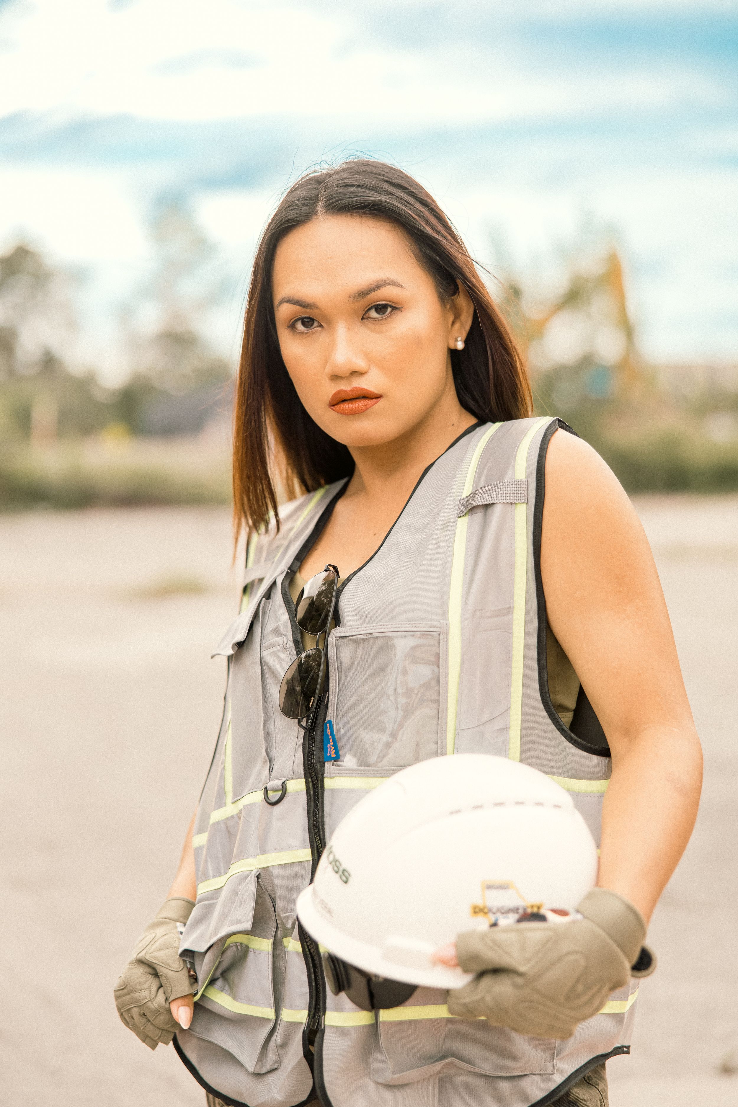 Professional in safety vest and gloves reviewing paperwork at outdoor location.
