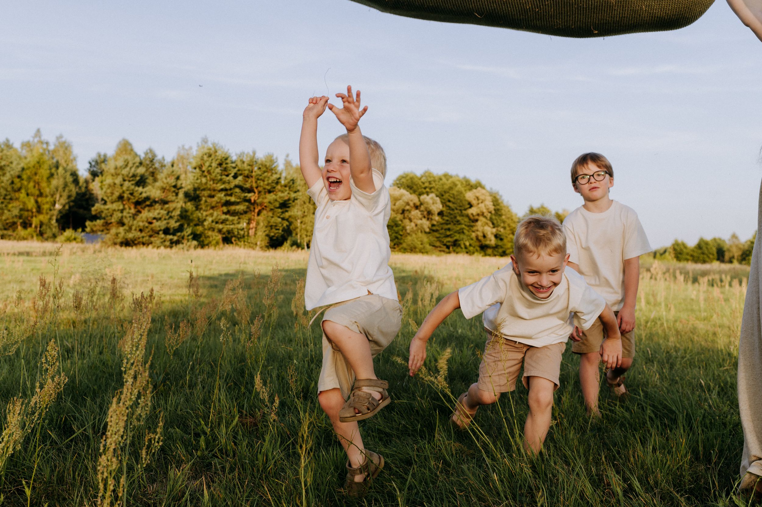 Family members sitting together in a sunny meadow with tall grass.