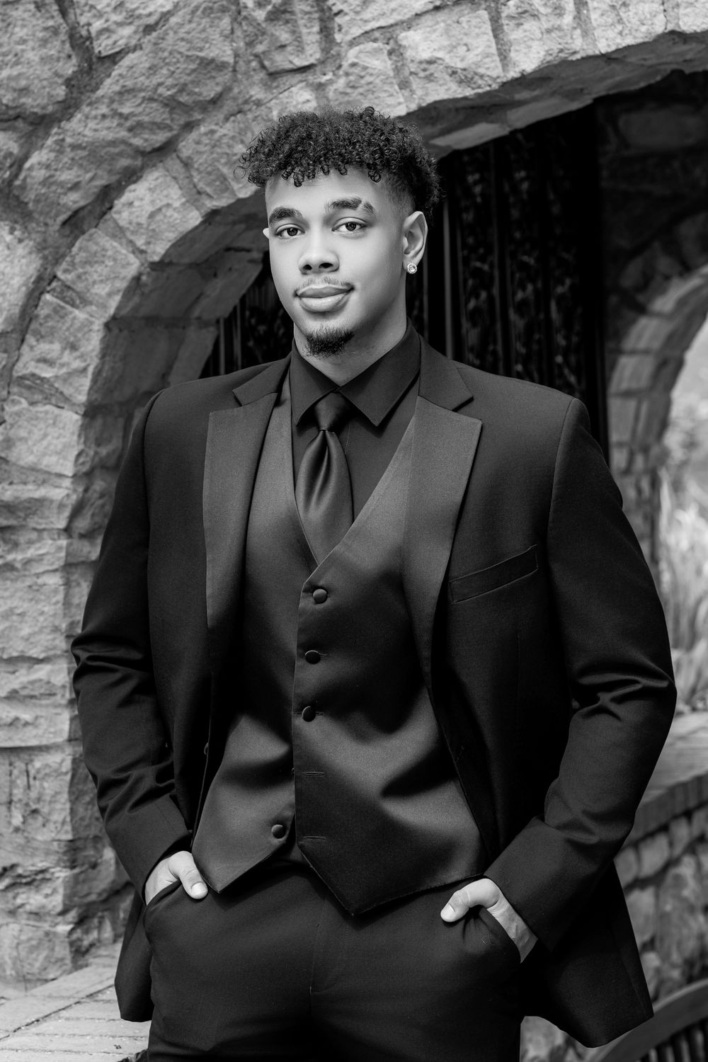 Professional photo series featuring five black and white portraits against a stone wall backdrop.