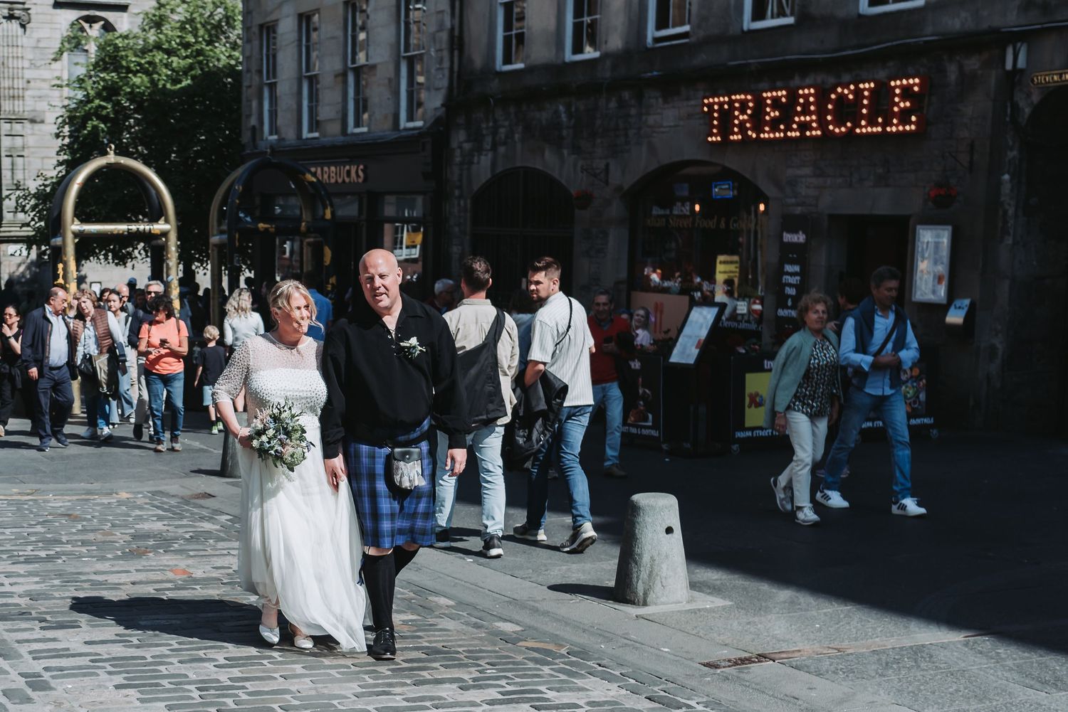 Wedding couple walking past the Treacle sign on Edinburgh's Royal Mile.