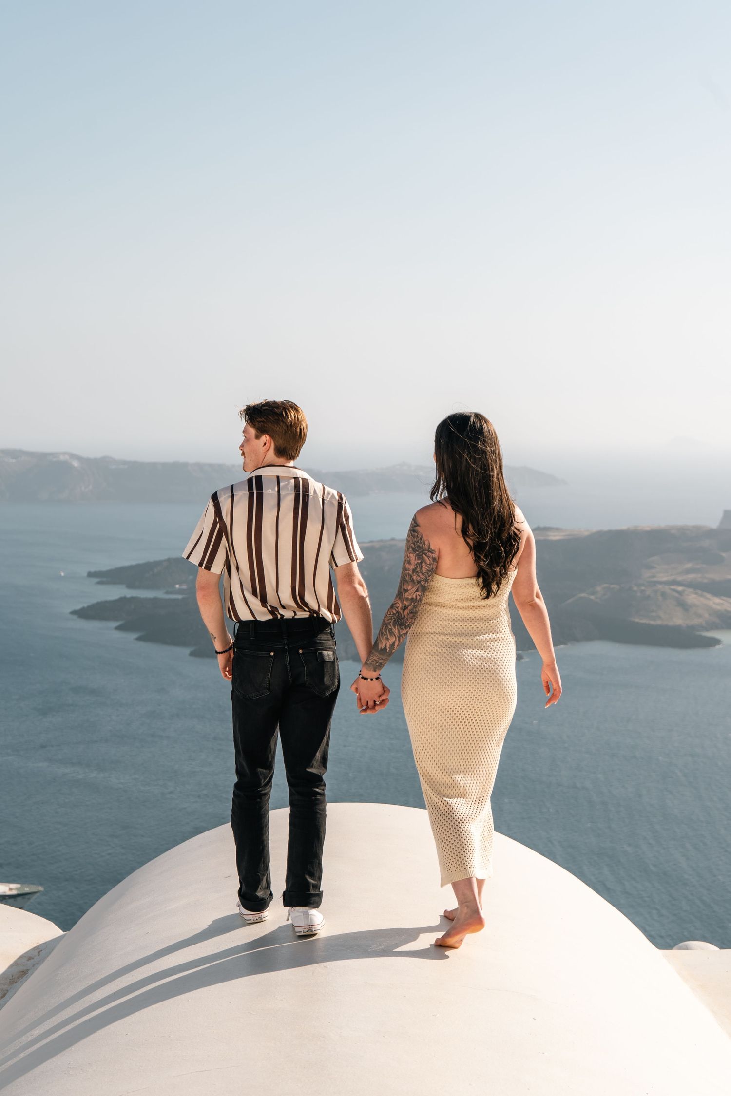 Couple embracing while watching sunset over Mediterranean waters.