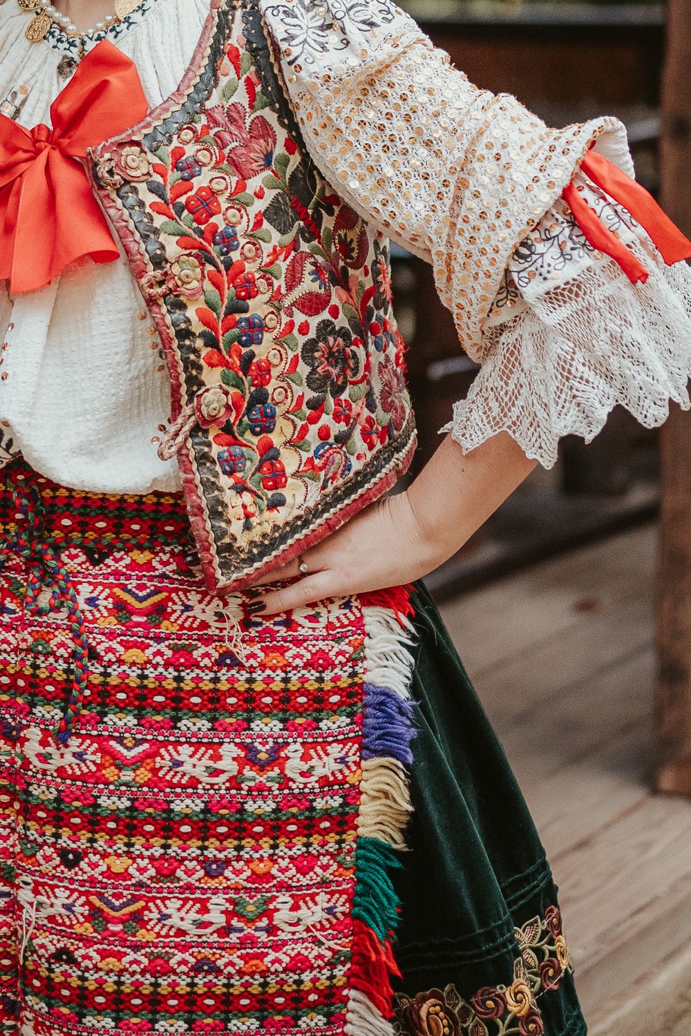 Close-up detail of ornate folk costume showing floral embroidery and lace sleeves.