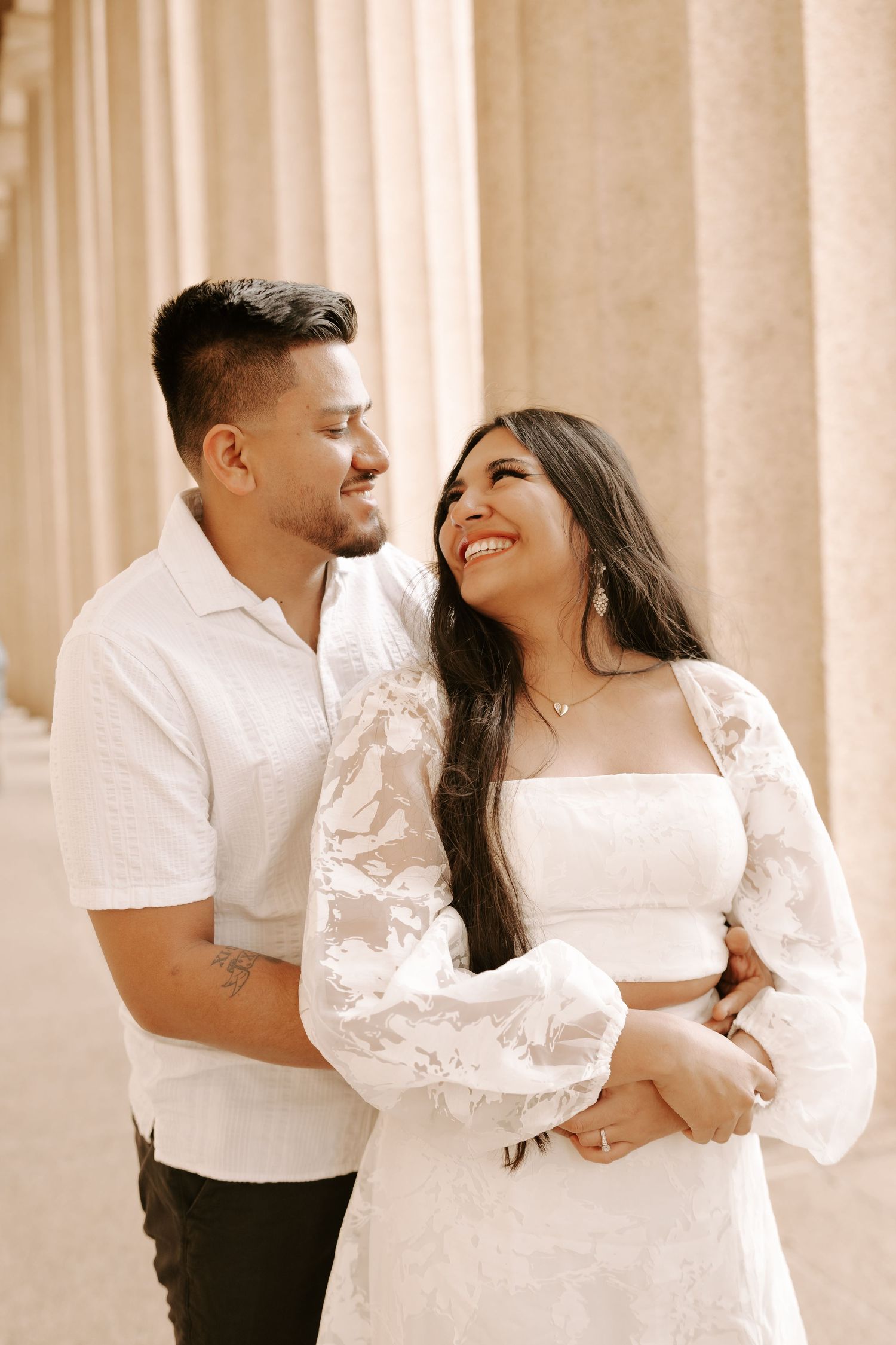 Couple in coordinated white outfits sharing intimate moments during their engagement photoshoot.