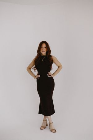 A person wearing a dress for a portrait photography session in front of a white studio backdrop.