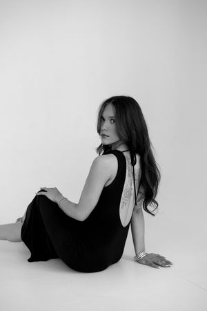 A person wearing a dress for a portrait photography session in front of a white studio backdrop.