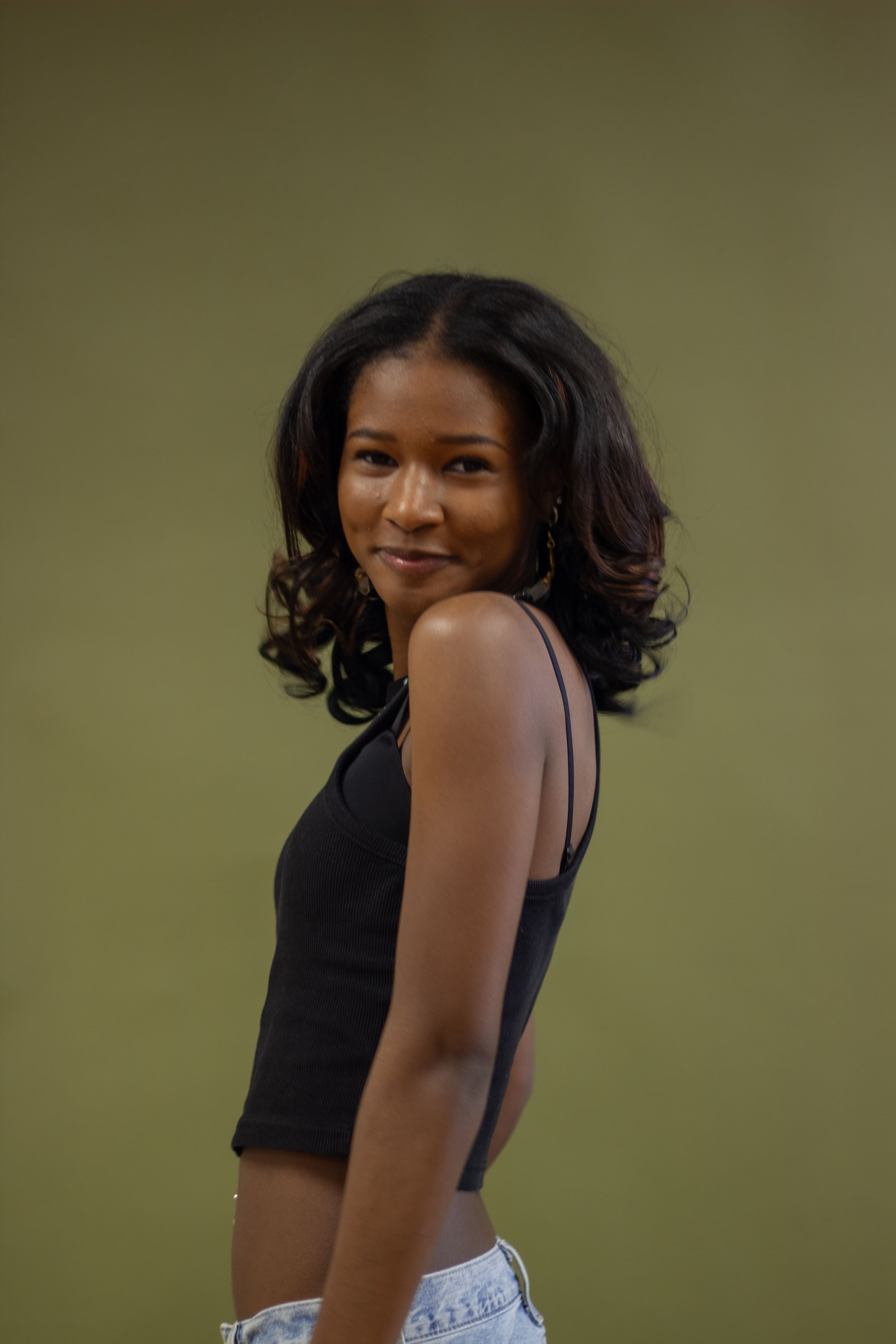 A series of profile photos showing someone in a black sleeveless top posing against a green-tinted background.Branding photos, senior photos