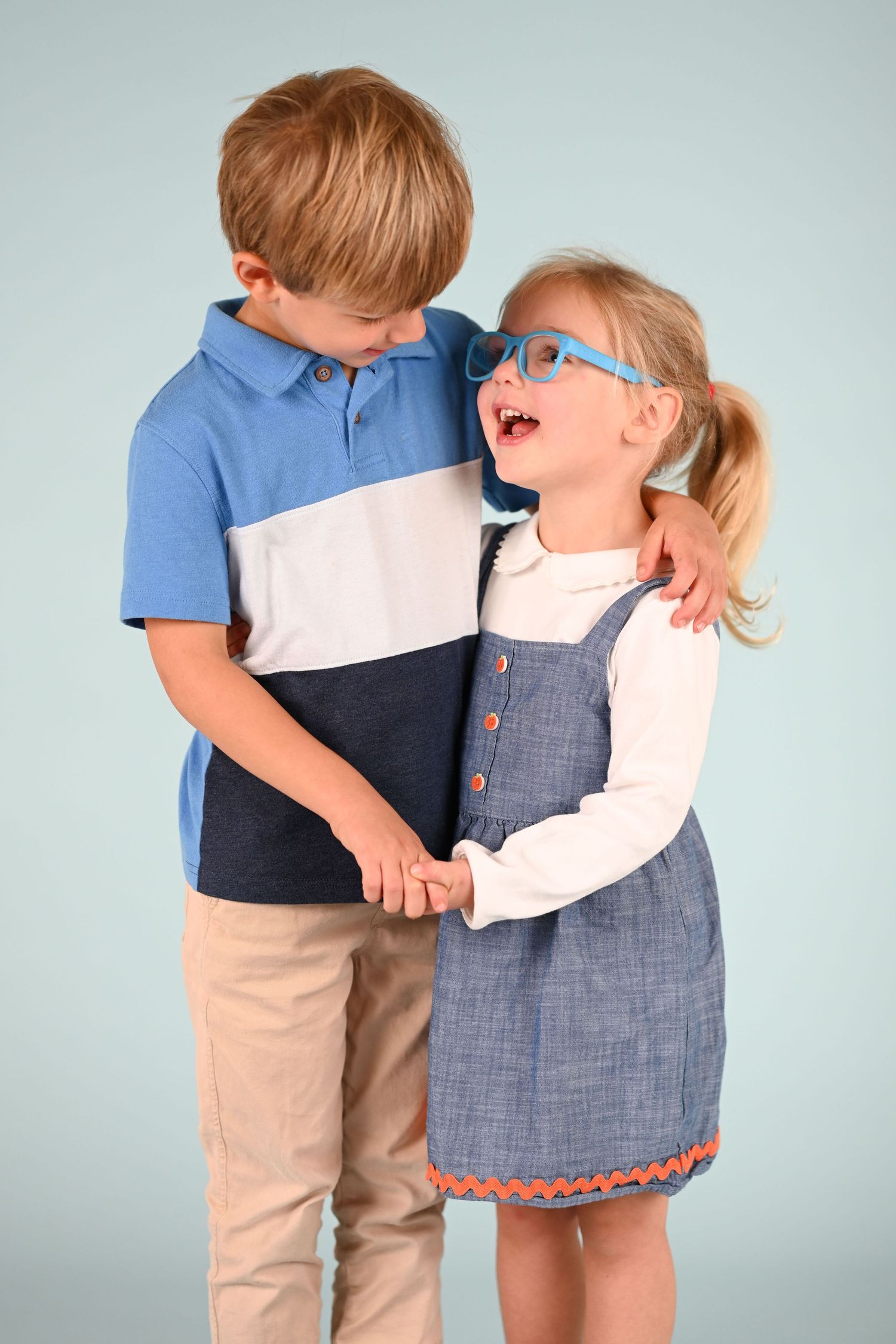 Children in coordinating blue and white outfits sharing playful moment together.