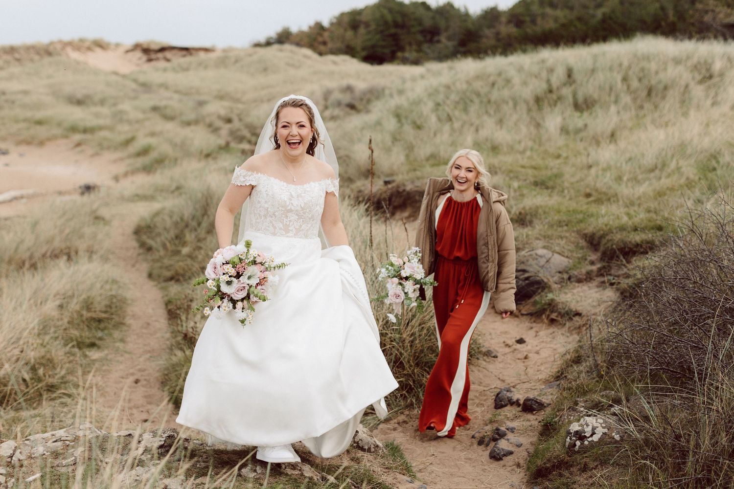 A couple walks together through scenic grassy hills on a cloudy day.