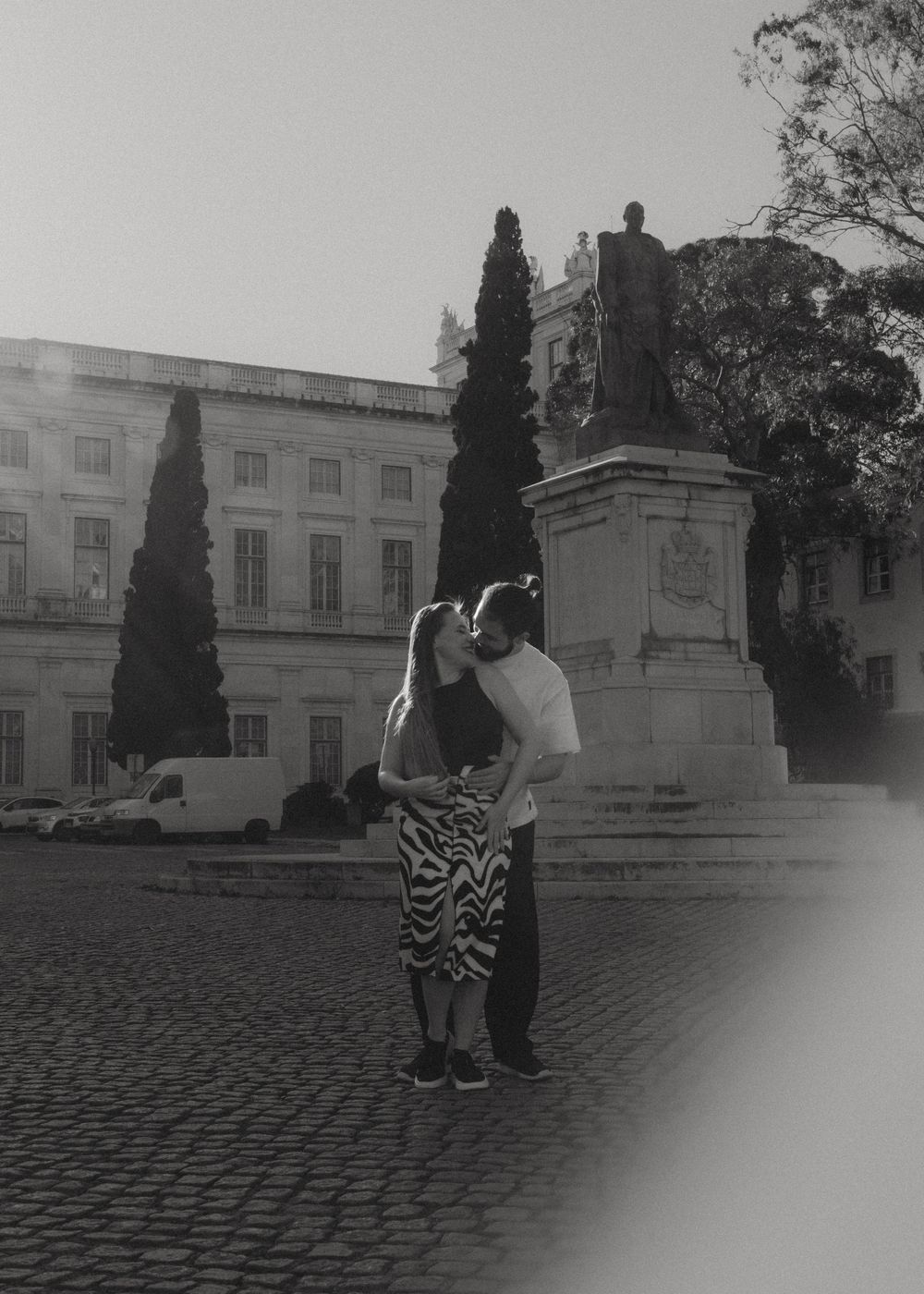 A romantic dance pose on cobblestone ground with classical architecture in the background.