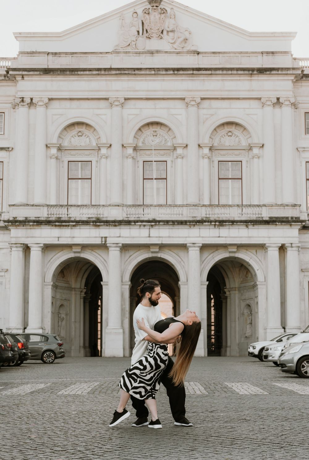 A romantic dance pose in front of a grand white classical building.
