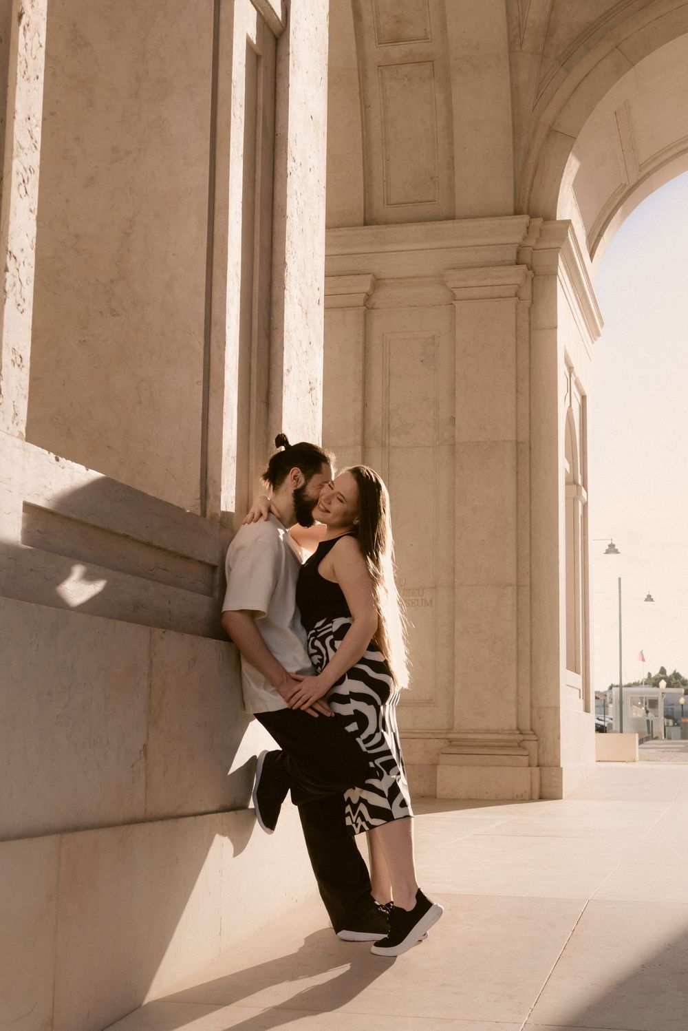 Intimate dance sequence captured under ornate white stone archways with dramatic natural lighting.